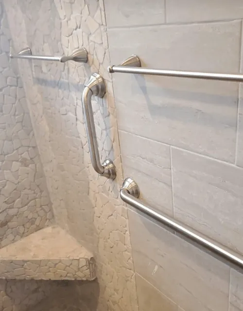 Angled and vertical grab bars in a stone corner shower